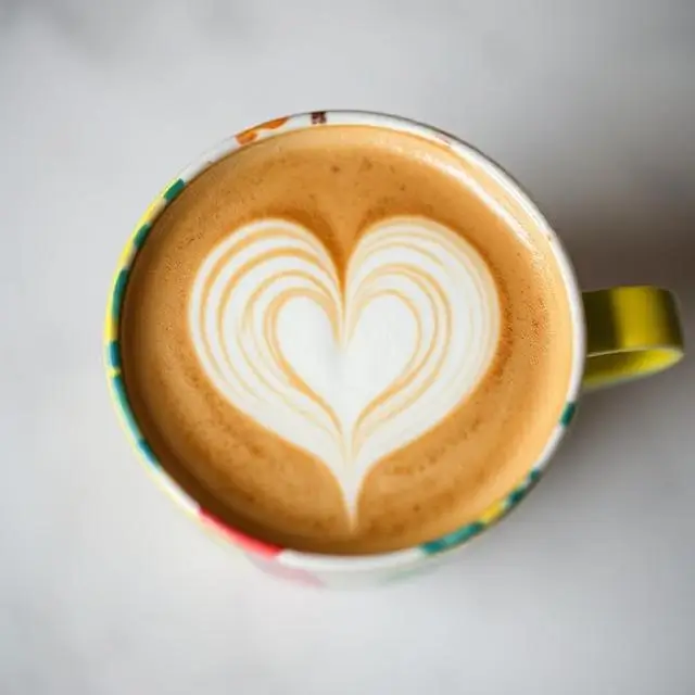 A colorful cup with a perfect heart-shaped latte art design.